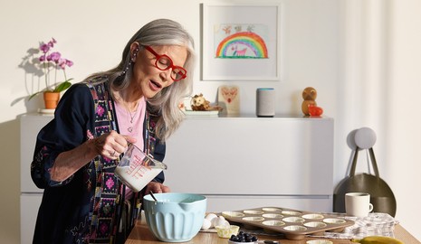 elderly lady talkin to voice assitant while cooking